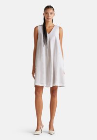 Ärmelloses weißes Leinenkleid mit V-Ausschnitt, lockerer Silhouette und knie-langer Saum. Einfaches, minimalistisches Design mit einer weichen Textur.