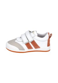 Zapatilla blanca con acentos de ante marrón, capuchón del dedo del pie gris y dos correas de Velcro. Presenta una suela de goma texturizada y una lengüeta en el talón.