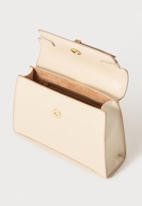 Bolso de mano de piel beige con forma estructurada, herrajes dorados y un único compartimento con un forro de tela marrón y un bolsillo con cremallera.