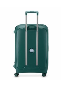 Valise rigide verte avec une poignée télescopique étendue et quatre roues multidirectionnelles, se tenant debout sur un fond blanc.