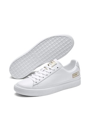 Par hvide Puma sneakers med strukturerede gummisåler, gyldent Puma-logo på tungen og siden, og hvide snørebånd.