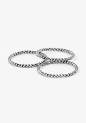 Conjunto de tres anillos de metal retorcido, de color plateado, con un acabado suave y un patrón en espiral, reposando sobre una superficie reflectante.