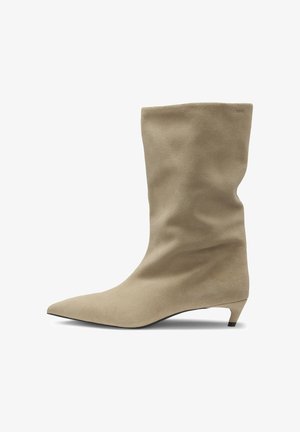 Beige Wildleder-Ankle Boot mit spitzem Zeh, weicher Textur und lässigem Design. Verfügt über einen niedrigen, konischen Absatz und minimalistische Branding-Details.