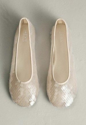 Béžové balerínky s flitrami, hladkým povrchom, zaoblenou špičkou a elastickým lemom. Sú zdobené lesklými, polopriehľadnými ozdobami.
