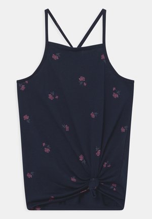 Marineblauw mouwloos topje met dunne gekruiste bandjes, kleine roze bloemenprint verspreid, en de voorkant van de stof onderaan geknoopt.