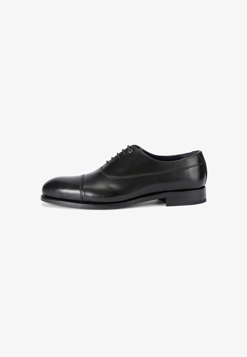 Chaussure Oxford formelle en cuir noir avec laçage fermé et petit talon, vue de côté sur fond blanc.