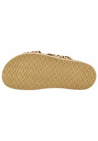 Sole sandálů v hnědé gumě se zigzagovým vzorem. Zlatý řetězový detail přes horní část, ukazující plochý design vhodný pro neformální nošení.
