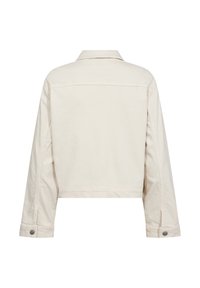 Veste courte couleur crème en toile de coton. Présente un col, des manches longues et des accents de boutons argentés aux poignets. Texture lisse.