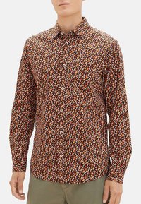 Langarm blouse met een veelkleurig geometrisch patroon op een donkerbruine achtergrond. Zonder naden, met een standaard kraag.