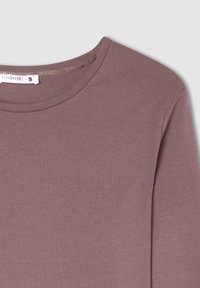 Mauve bawełniana koszulka z okrągłym dekoltem i krótkimi rękawami, o gładkiej fakturze i minimalnych detalach szwowych. Widoczna metka rozmiaru.