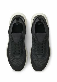 Baskets en maille noire avec une tige texturée, une fermeture à lacets et une semelle en caoutchouc gris clair. Elles disposent d'une languette au talon pour un enfilage facile.