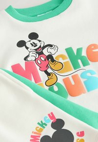 Weißes Sweatshirt mit grünem Kragen, das bunten "Mickey Mouse"-Text und eine klassische Illustration der Figur Mickey Mouse zeigt.