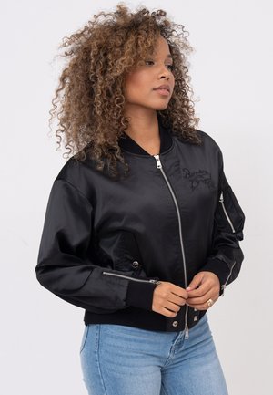 Schwarze Bomberjacke mit Reißverschluss vorne, gerippten Manschetten und Seitentaschen, mit einem gestickten Logo auf der Brust und glatter Stofftextur.