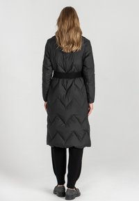 Czarna kurtka puchowa z paskiem, z przeszywaniem w zygzak. Długi fason o gładkiej fakturze i kontrastowym matowym wykończeniu.