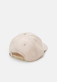 Beige baseball sapka ívelt karimával, textúrált anyagból, állítható snapback záródással és látható varrási részletekkel.