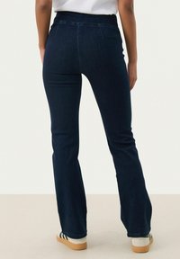 Donkerblauwe flared jeans met een middelhoge tailleband, gemaakt van denim stof. Heeft een gladde textuur en een klassieke vijf-pocket ontwerp.