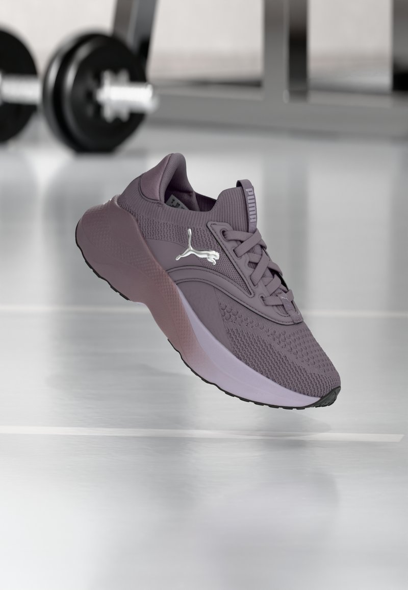 Pantof diversificare violet, cu un superior din plasă respirabilă, modele texturate și o talpă intermediară roz contrastantă. Are logo-ul brandului pe lateral.