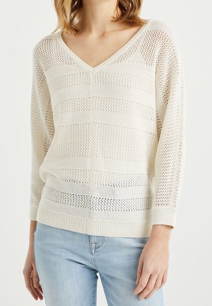 Pull en tricot léger crème, avec un col en V, des manches longues et un motif rayé de sections ajourées et solides.