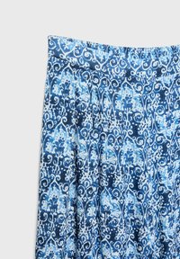 Close-up of blue and white patterned skirt with intricate floral and swirl designs and an elastic waistband.