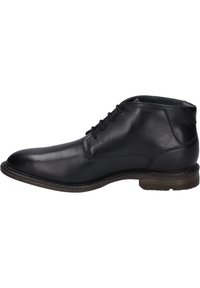 Botas de cuero negro hasta el tobillo con un acabado suave, puntera redondeada, cierre de cordones y un tacón bajo marrón. Un simple pespunte acentúa el diseño.