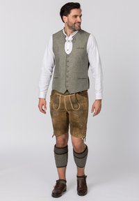 Traditionelles deutsches Outfit bestehend aus einer grauen Leinenweste, braunen Lederhosen mit aufwendigen Stickereien und gemusterten knielangen Socken.