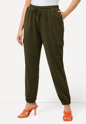 Pantaloni cargo verde oliva con vita e polsini elasticizzati, dotati di tasche laterali e texture liscia. Abbinati a tacchi arancioni con cinturini.