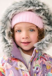 Lila Pufferjacke mit floralem Muster, grauer Kunstpelzkapuze und rosa gerippter Mütze. Auffälliger Drachenakzent auf der Brust.