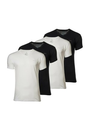 Young man standing barefoot wearing a black short-sleeve shirt and light gray long pants against a plain white background.