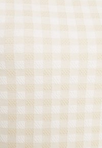 Tessuto a quadri beige e bianco con un motivo testurizzato, caratterizzato da quadrati in blocco alternati in diverse sfumature per un aspetto tessuto sottile.