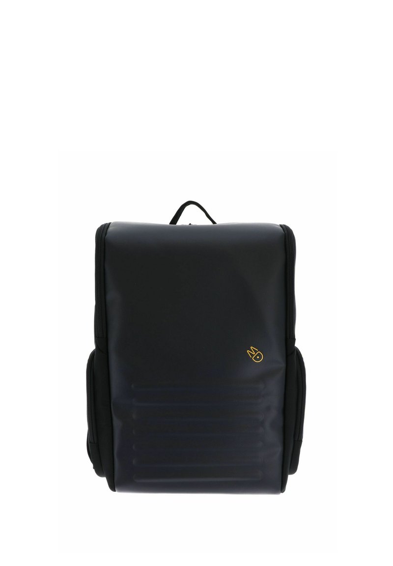 Sac à dos noir avec une finition lisse et mate, comportant une poche zippée à l'avant, des poches latérales et un petit logo doré. Conception structurée et rectangulaire.
