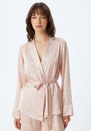 Ensemble de pyjama en satin rose avec des pois blancs. Comprend un design enveloppant, des manches longues et une ceinture nouée à la taille, avec un passepoil contrastant sur les poignets.