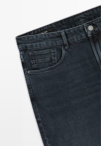 Jeans in denim scuro con chiusura a zip e bottone, tasche frontali, dettagli di cucitura sottili e gamba dritta.
