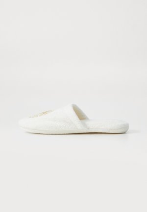 White terry cloth slipper with a rounded toe, open back, and gold embroidered detail on the top. Soft texture, flat sole.