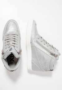 Sølv høye sneakers med teksturerte overflater, perforeringer, glidelåser på siden og lys grå snøringer. Gummisåle med subtil merkevare.