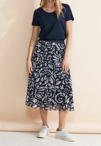 Námořnické tričko v kombinaci s dlouhou, vzdušnou sukní s námořnicko-bílým květinovým vzorem. Sukně má elastický pas a průsvitnou texturu.