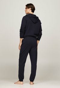 Dunkelblauer Hoodie und Sweatpants-Set aus weichem Stoff. Mit Kapuze, langen Ärmeln und Bündchen an den Knöcheln. Subtiles Logodetail auf der Hose.