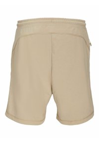 Shorts de sport beiges avec une taille élastique, des poches latérales et des détails cousus, présentant une texture de tissu lisse.