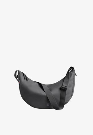 Czarna, półksiężycowa torba na ramię z regulowanym paskiem, zamkiem błyskawicznym i małymi bocznymi metkami na białym tle.