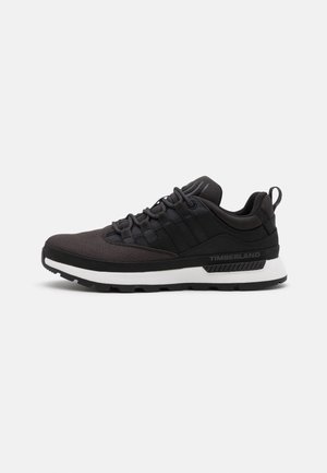 Czarne buty sportowe z teksturowaną cholewką, elastycznym systemem sznurowania, kontrastującą białą podeszwą środkową oraz gumową podeszwą z rowkami dla lepszej przyczepności.