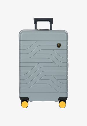 Grauer Hartschalenkoffer mit schwarzem Griff, gelben Rollen und Wellenmuster auf der Vorderseite.