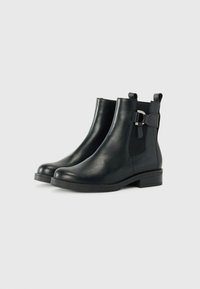 Botines de cuero negro con paneles laterales elásticos, un acréscimo de hebilla, punta redondeada y un tacón bajo apilado. Textura suave y diseño elegante.