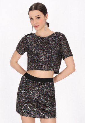 Černý croppovaný top a odpovídající miniskirt, oba pokryté barevnými flitry, s širokým černým pasem a krátkými rukávy.