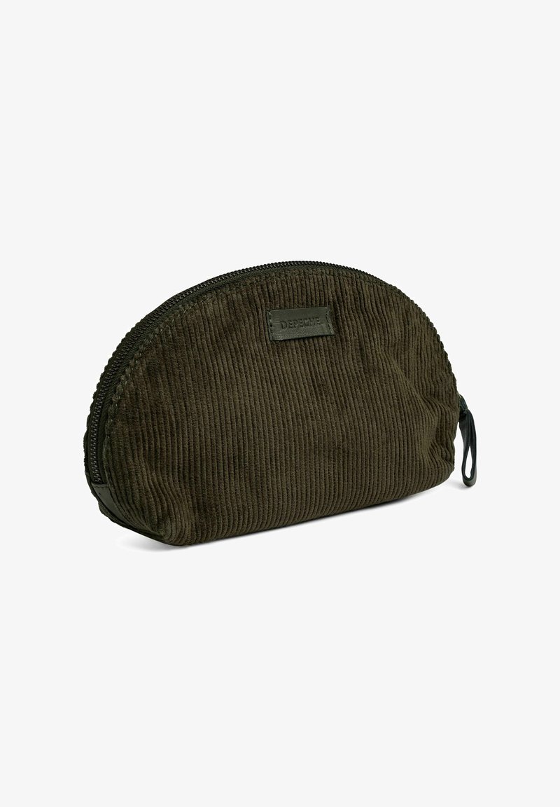 Donkergroene corduroy tas met een ronde vorm, voorzien van een ritssluiting en een leren merkpatch aan de voorkant. Getextureerd oppervlakdetail.