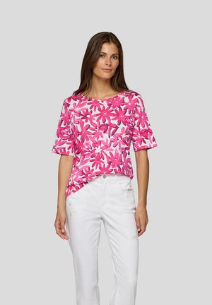Short-sleeve shirt in pink with a floral pattern, featuring a round neckline. Paired with white distressed jeans.