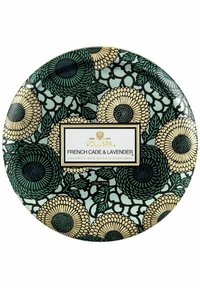 Kokosvaxbete i en rund behållare med ett blommönster i grönt, svart och guld, med en vit etikett som visar produktinformation.