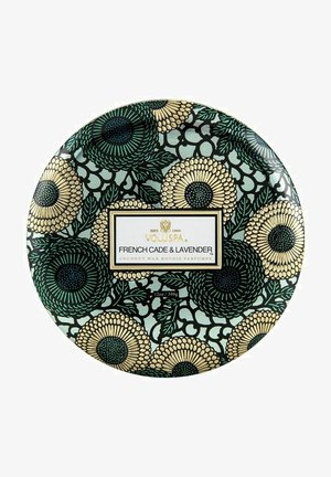 Kokosvokslys i en rund beholder med et blomstermønster i grøn, sort og guld, med en hvid label med produktinformation.