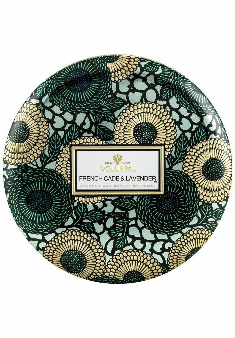 Kokosvaxbete i en rund behållare med ett blommönster i grönt, svart och guld, med en vit etikett som visar produktinformation.