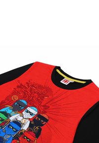 Rotes Grafik-T-Shirt mit einer Comic-Illustration von sechs Ninja-Charakteren in verschiedenen Farben. Schwarze Ärmel, runder Kragen und weicher Stoff.