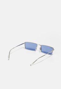 Fyrkantiga solglasögon med blåa linser, silvermetallram, smala skalmar och klara glas. Har logotypdetalj på vänster lins.