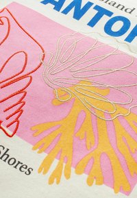 Design textile abstrait mettant en avant une broderie en forme de corail en orange et doré sur un fond rose, avec un texte bleu audacieux et un tissu crème.